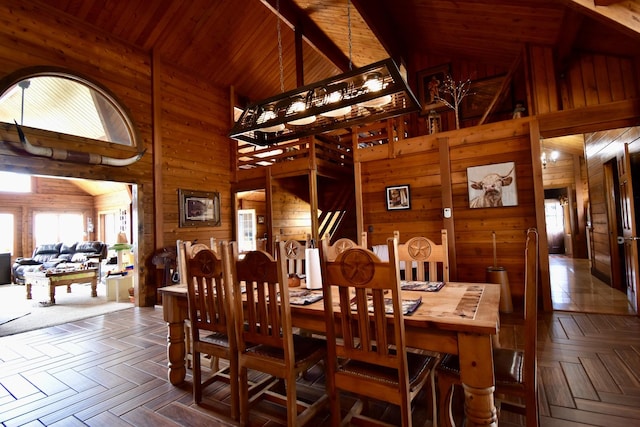 dining room with high vaulted ceiling and wood walls