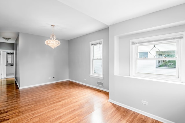 unfurnished room with hardwood / wood-style floors and an inviting chandelier