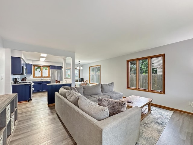 living area with a chandelier, light wood-style flooring, and baseboards