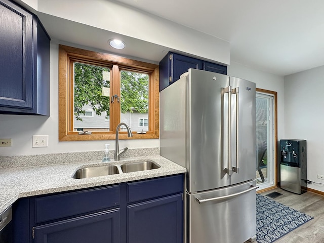 kitchen with visible vents, blue cabinetry, high quality fridge, wood finished floors, and a sink