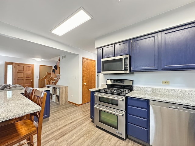 kitchen with blue cabinets, visible vents, light wood-style flooring, open floor plan, and stainless steel appliances