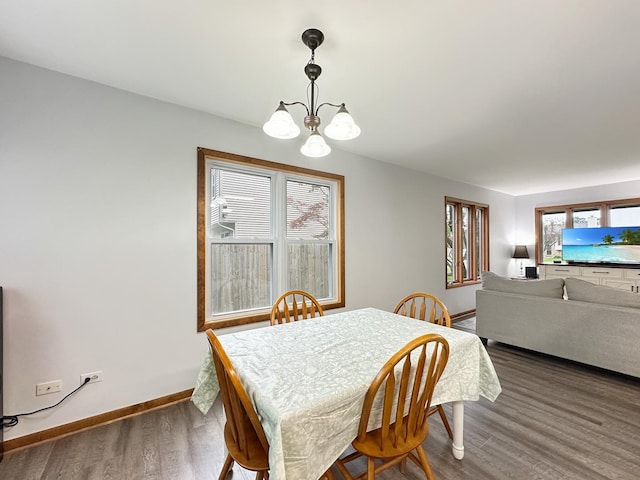 dining area featuring baseboards, an inviting chandelier, and wood finished floors