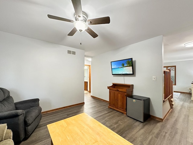 living area featuring visible vents, baseboards, dark wood-type flooring, and ceiling fan