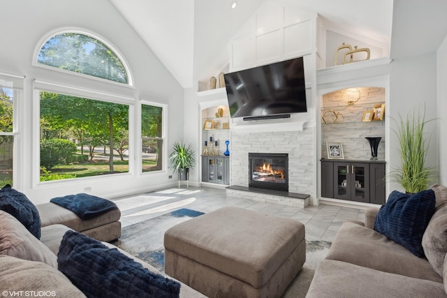 living room with a stone fireplace and high vaulted ceiling