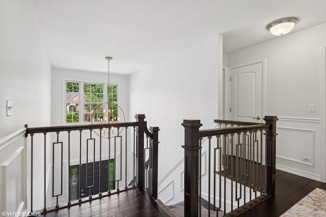 corridor with dark wood-type flooring and a notable chandelier