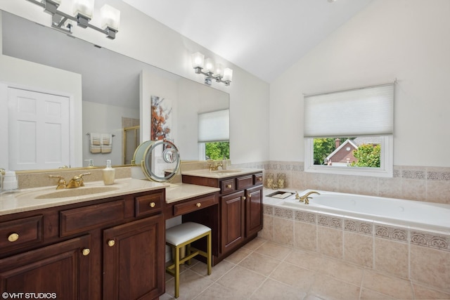 bathroom with tile patterned flooring, vaulted ceiling, a relaxing tiled tub, and vanity