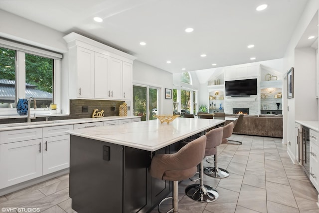 kitchen with white cabinetry, a center island, a breakfast bar area, and a fireplace