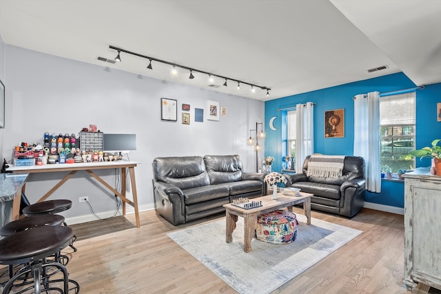 living room with rail lighting, light hardwood / wood-style flooring, and plenty of natural light