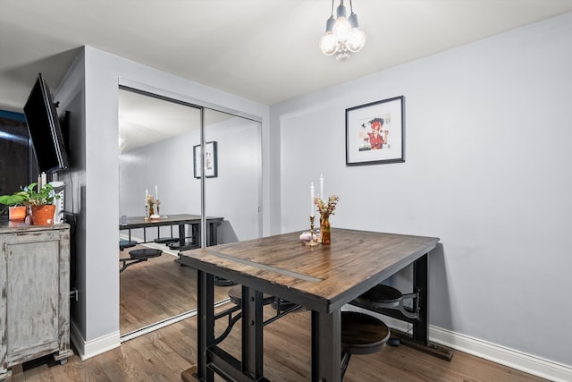 dining space featuring dark wood-type flooring and an inviting chandelier