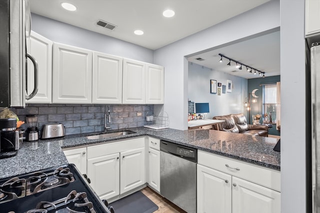 kitchen featuring dark stone counters, sink, white cabinets, appliances with stainless steel finishes, and tasteful backsplash