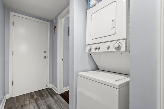 laundry area with dark wood-type flooring and stacked washer / drying machine