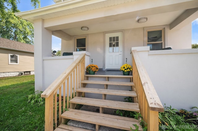 doorway to property with a lawn and stucco siding