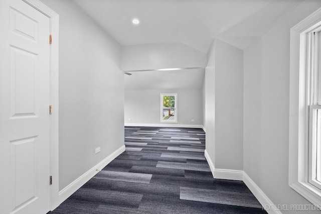 corridor featuring lofted ceiling and baseboards