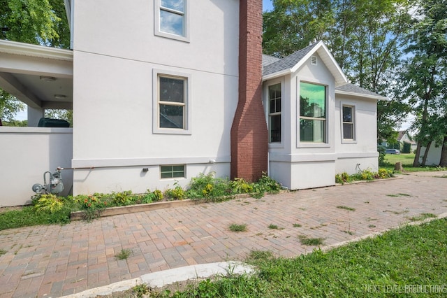 view of side of home with a patio area, a chimney, and stucco siding