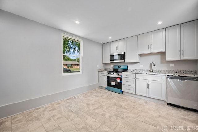 kitchen featuring stainless steel appliances, sink, light stone countertops, white cabinets, and light tile patterned floors