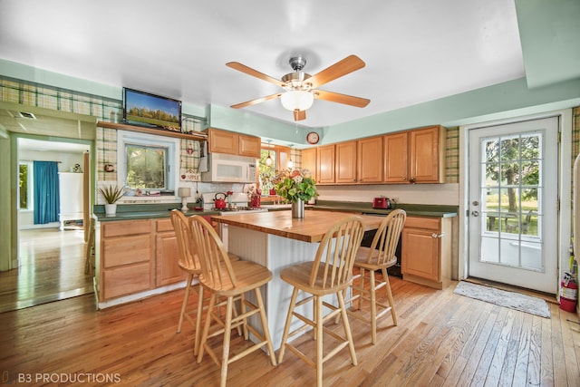 kitchen featuring ceiling fan, light hardwood / wood-style flooring, wooden counters, and a kitchen island