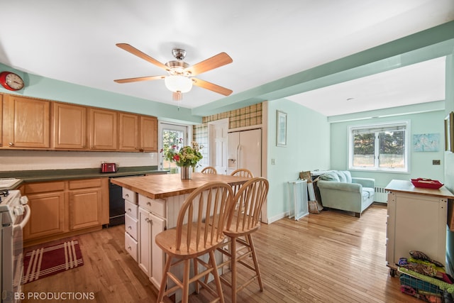 kitchen with plenty of natural light, light hardwood / wood-style flooring, white refrigerator with ice dispenser, and stove