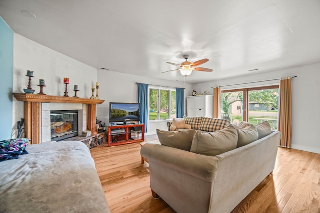 living room with light hardwood / wood-style floors, ceiling fan, and a fireplace