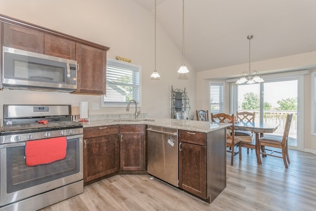 kitchen with light stone counters, pendant lighting, a wealth of natural light, and appliances with stainless steel finishes