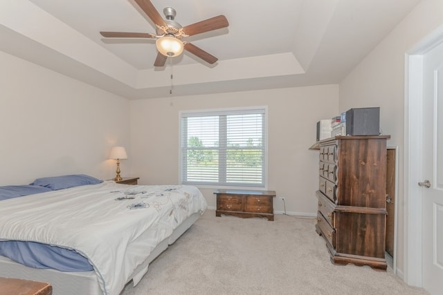 carpeted bedroom with ceiling fan and a tray ceiling