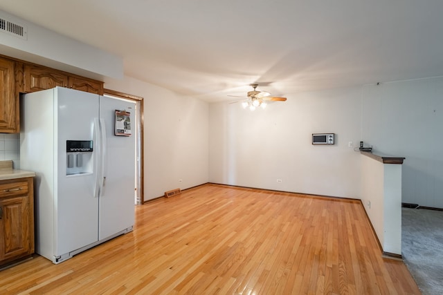 kitchen with ceiling fan, white fridge with ice dispenser, and light hardwood / wood-style floors