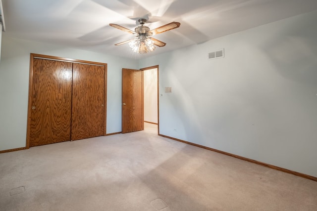 unfurnished bedroom with a closet, light colored carpet, and ceiling fan