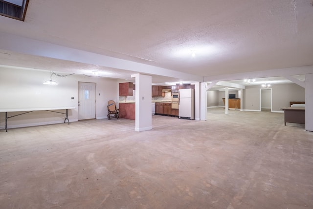 basement with a textured ceiling and white fridge