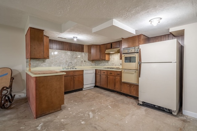 kitchen featuring decorative backsplash, a textured ceiling, white appliances, and sink