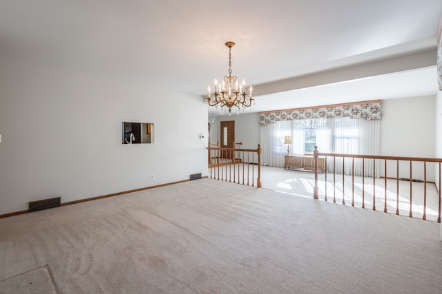 carpeted empty room featuring a notable chandelier