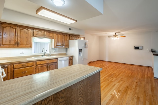 kitchen with white appliances, sink, light hardwood / wood-style flooring, ceiling fan, and tasteful backsplash