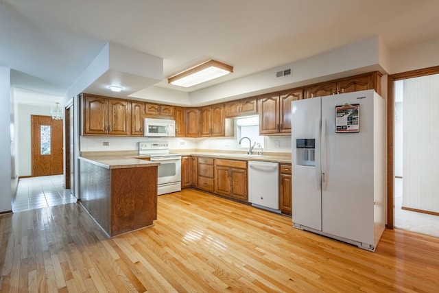 kitchen featuring light wood-type flooring, white appliances, sink, and tasteful backsplash