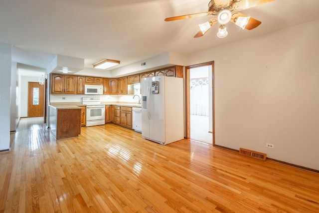 kitchen with light wood-type flooring, white appliances, ceiling fan, and sink