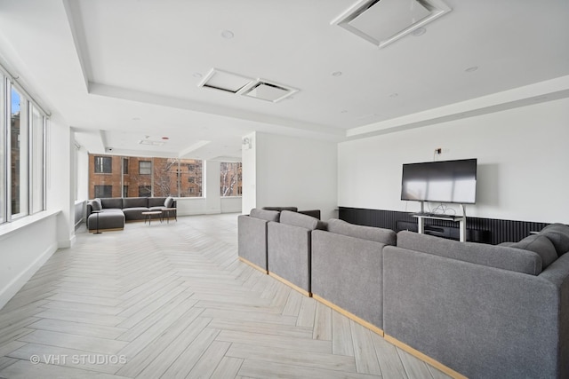 living room featuring a tray ceiling, a healthy amount of sunlight, and attic access