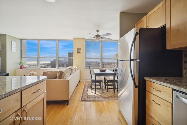 kitchen featuring light wood finished floors, stone countertops, light brown cabinetry, stainless steel appliances, and ceiling fan