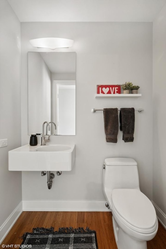 half bathroom featuring baseboards, toilet, and wood finished floors