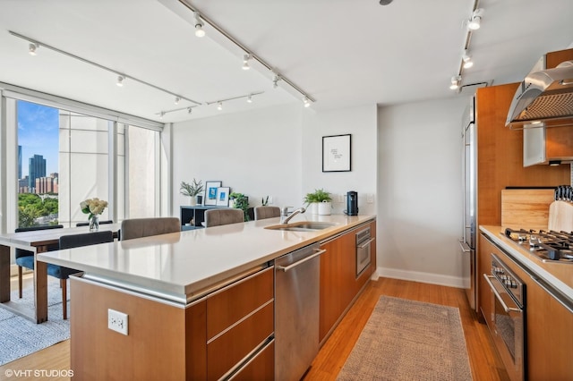 kitchen with range hood, brown cabinets, appliances with stainless steel finishes, modern cabinets, and a peninsula