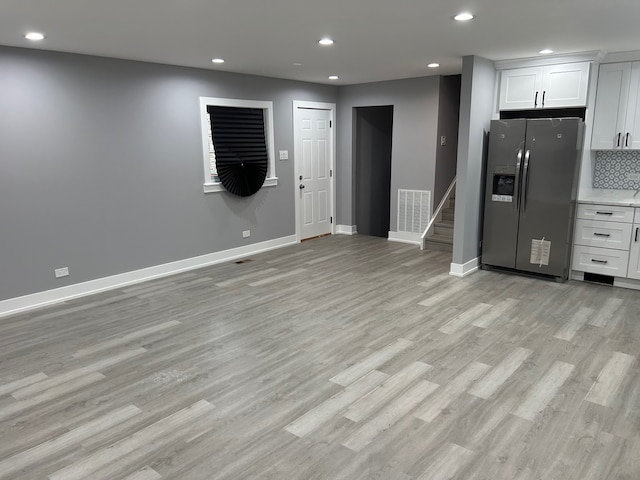 kitchen with decorative backsplash, light hardwood / wood-style floors, stainless steel fridge with ice dispenser, and white cabinetry