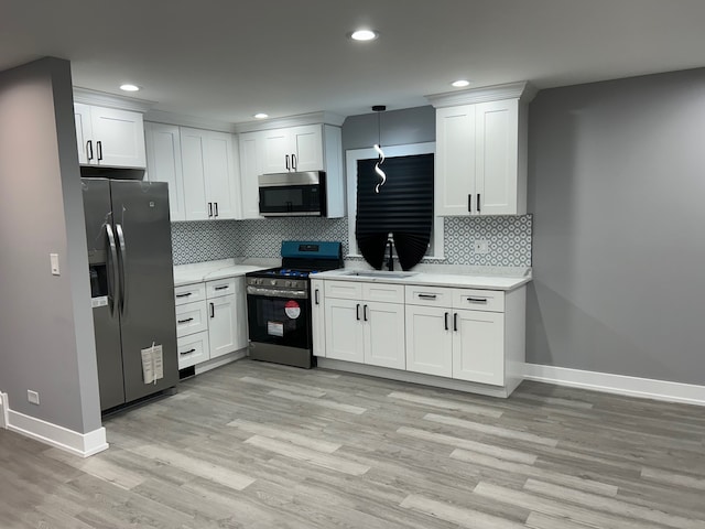 kitchen featuring appliances with stainless steel finishes, light hardwood / wood-style floors, white cabinets, and backsplash