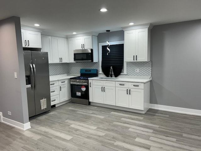 kitchen with white cabinetry, sink, decorative light fixtures, and appliances with stainless steel finishes