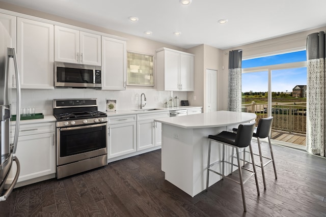 kitchen with backsplash, appliances with stainless steel finishes, a kitchen island, white cabinetry, and dark hardwood / wood-style floors