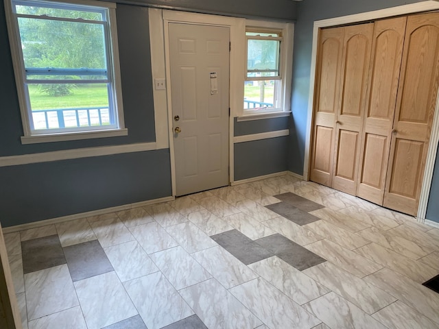 foyer entrance featuring marble finish floor, plenty of natural light, and baseboards