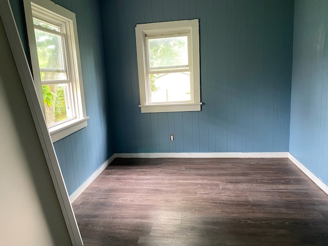 unfurnished room with dark wood-style floors, a wealth of natural light, and baseboards