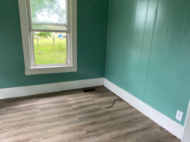 unfurnished room with wood finished floors, visible vents, and baseboards