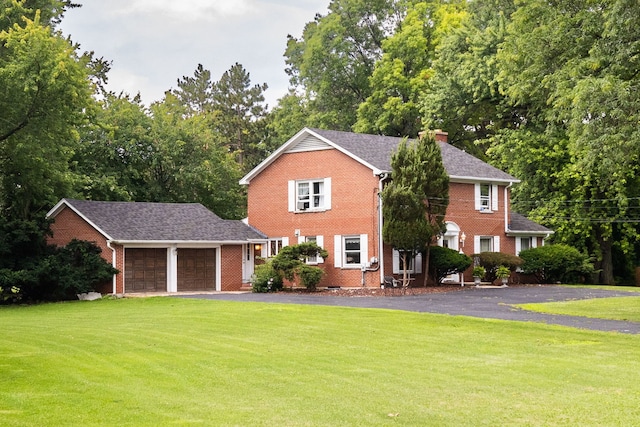 colonial inspired home featuring a front lawn and a garage