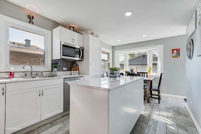 kitchen with white cabinets, sink, a kitchen island, light hardwood / wood-style flooring, and stainless steel appliances