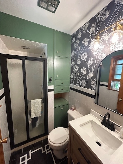 bathroom featuring a shower with door, toilet, tile walls, tasteful backsplash, and vanity