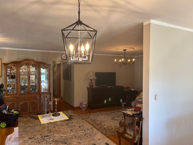 living room with crown molding, an inviting chandelier, and hardwood / wood-style floors