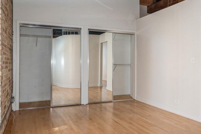 unfurnished bedroom featuring two closets and light hardwood / wood-style flooring