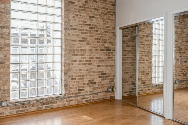 interior space featuring hardwood / wood-style flooring and brick wall