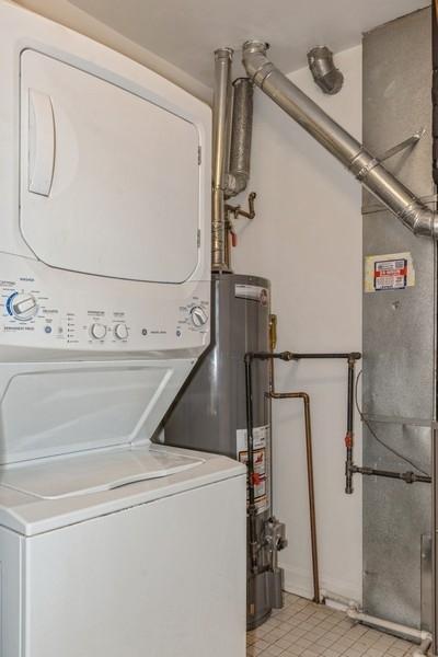 laundry room with stacked washer / drying machine and light tile patterned floors